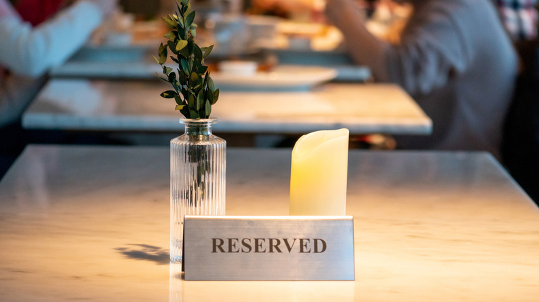 A reserved sign on an elegant restaurant table with a candle and potted plant