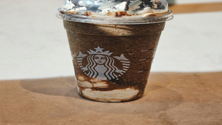 Starbucks Mocha Cookie Crumble Frappe, a dark brown blended drink topped with whipped cream and lots of chocolate drizzle