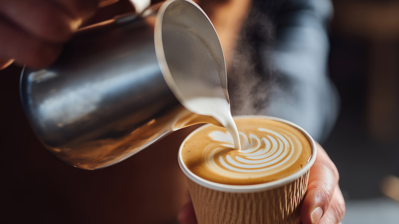 A barista pours steamed milk into a latte