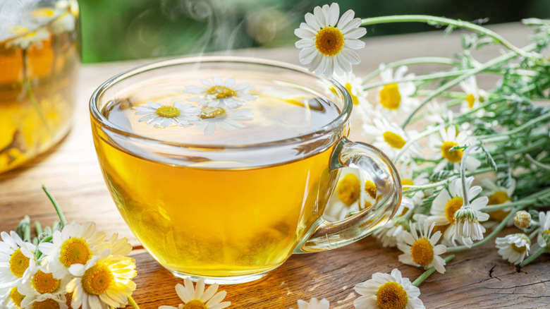 Cup of tea with chamomile flowers floating on top