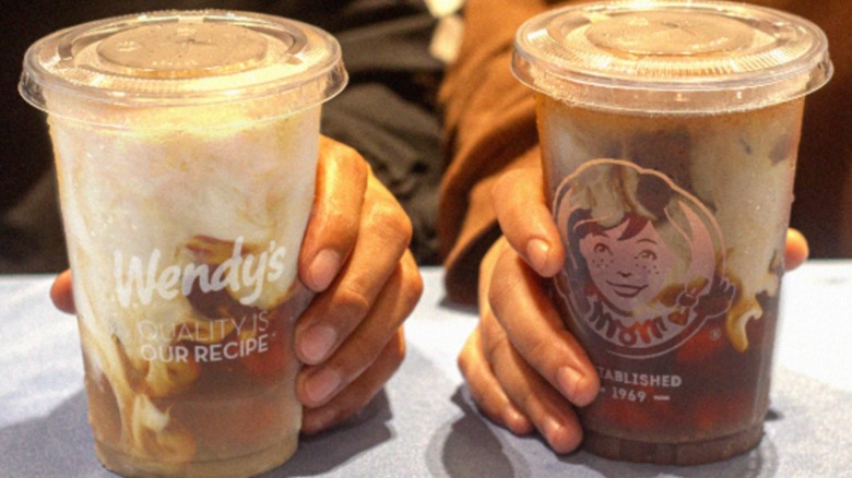Two hands holding a vanilla and chocolate Wendy's Frosty-ccino