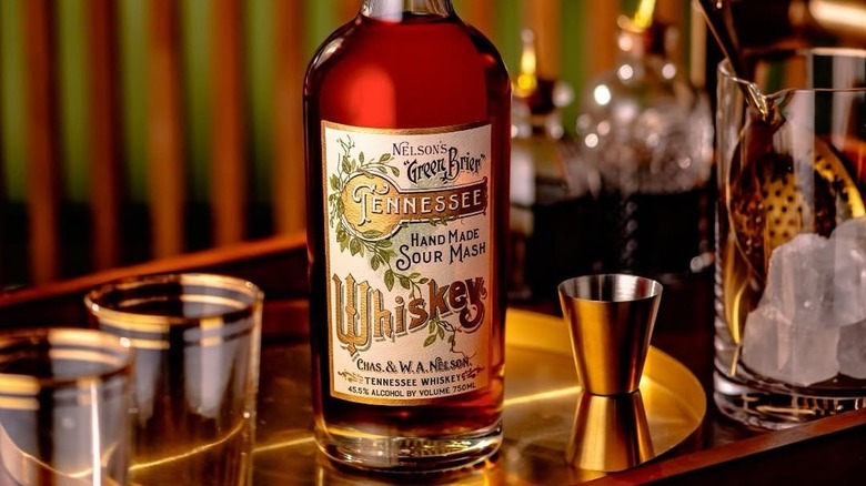 A bottle of Nelson's Green Brier on a serving tray surrounded by glasses and cocktail accessories