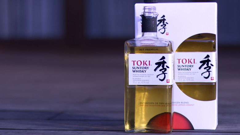 A bottle of Suntory Toki placed ahead of its box while placed on a wooden floor