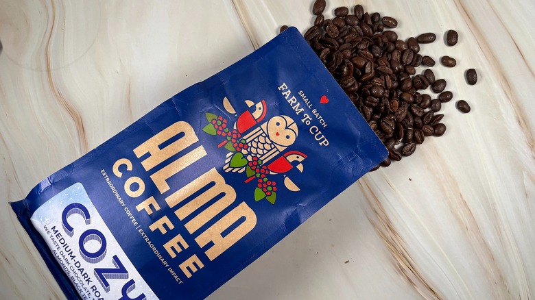 Top-down shot of coffee beans spilling out of bag of Alma Coffee holiday blend