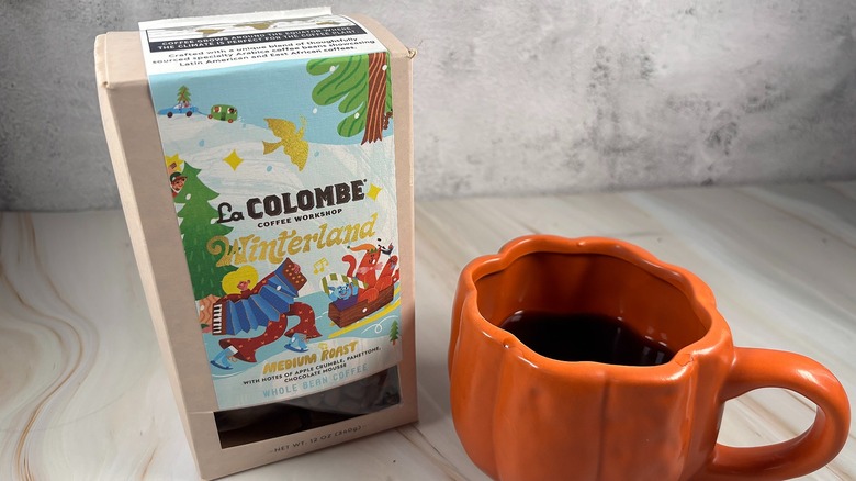 Box of La Colombe Winterland blend next to orange pumpkin mug of coffee on table