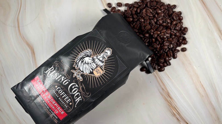 Top-down shot of coffee beans spilling out of bag of Rising C*** holiday blend