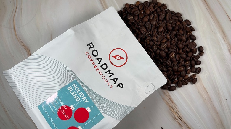 Top-down shot of coffee beans spilling out of bag of Roadmap holiday blend