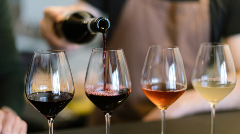 person pouring multiple glasses of wine