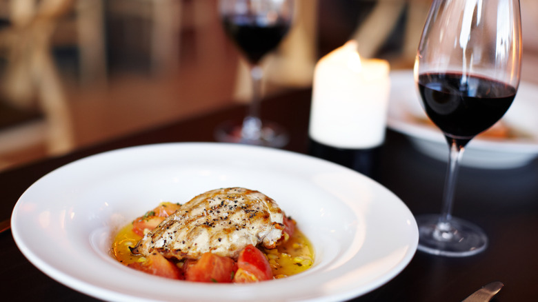 A chicken dish with a glass of red wine