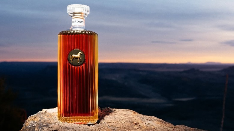 SirDavis American Whisky shown on a rock a dusk with a light shining on it