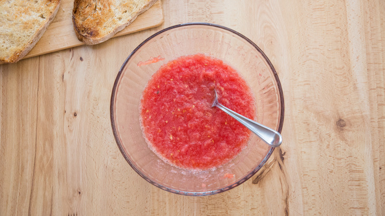 grated tomato in mixing bowl with metal spoon