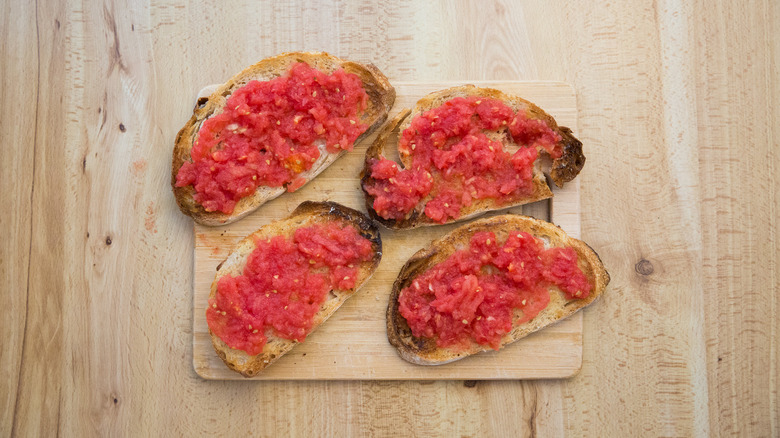tomato bread on wooden cutting board on wooden table