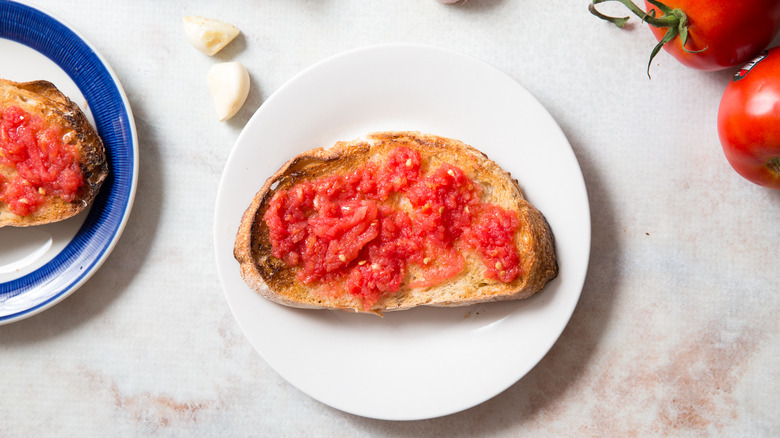 pan con tomate on plates next to garlic cloves
