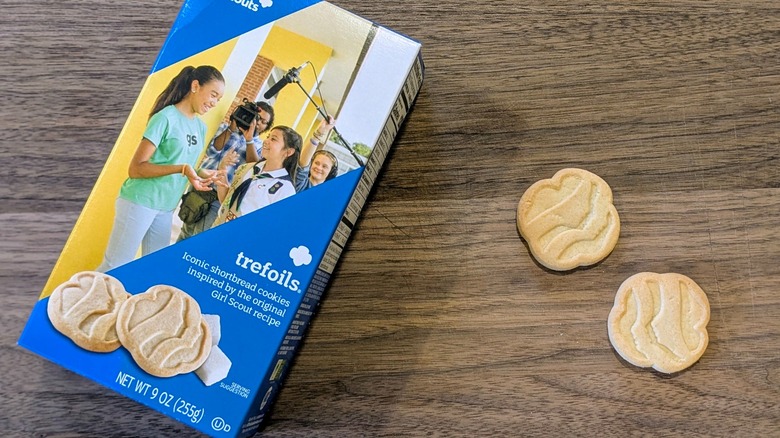 A box of Trefoils next to two small shortbread cookies on a wood board