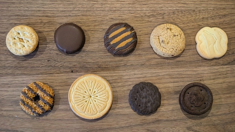 Nine different Girl Scout cookie varieites arranged in two lines on a wood board