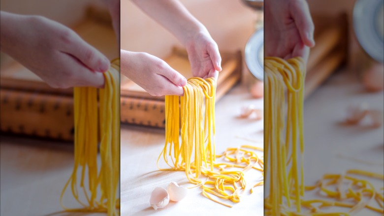 person holds Spaghetti alla chitarra in front of wooden tool