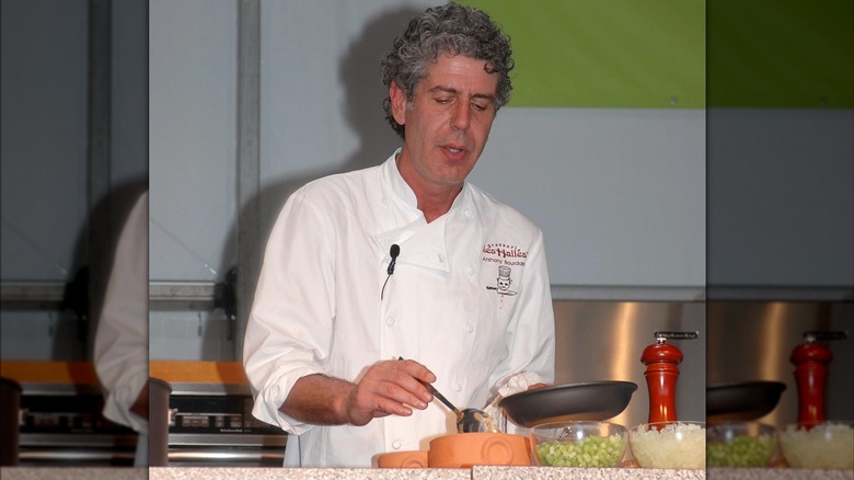 Anthony Bourdain holding a pan during a cooking demonstration
