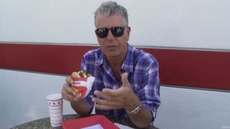 Anthony Bourdain holding an In-N-Out burger and talking