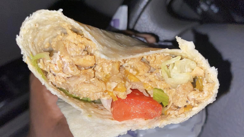 Someone holding a Classic Chicken Burrito from Del Taco