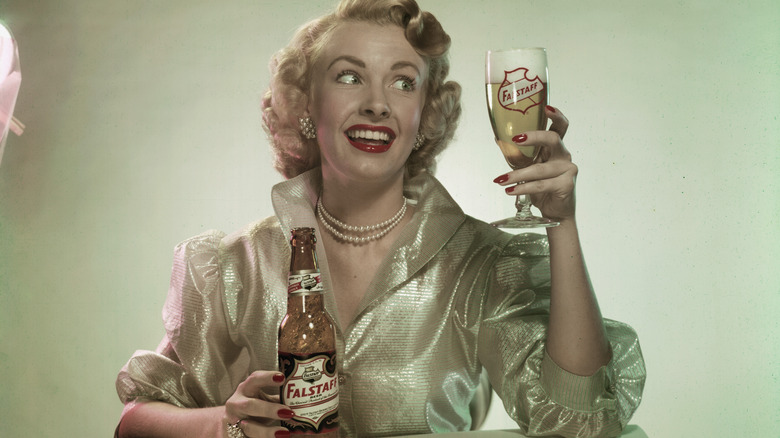 Woman in a sparkly top holing a glass and bottle of Falstaff beer