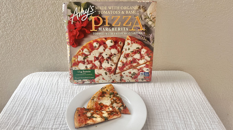 Amy's Margherita pizza slices on a plate with the box stacked against a wall