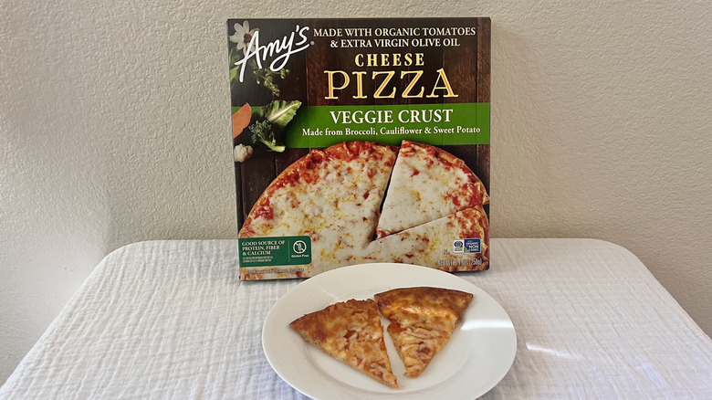 Amy's Veggie Crust Cheese box stacked against a wall with slices on a white plate in front