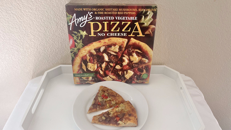 Amy's No Cheese Roasted Vegetable slices on a plate with the whole pizza box leaning against the wall behind it