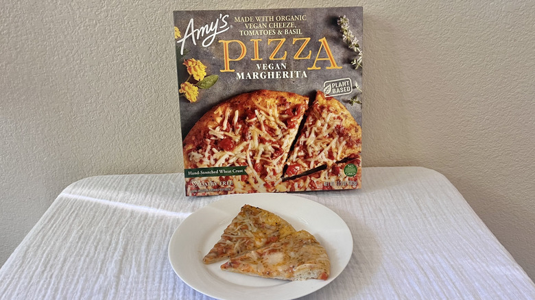 Vegan Margherita slices on a plate with a box behind it