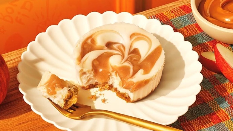 Popeyes Caramel Apple Cheesecake Cup sitting on scalloped white dish with golden fork