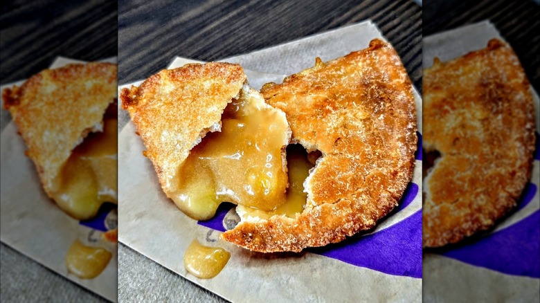 Taco Bell Caramel Apple Empanada broken in half sitting on paper wrapper