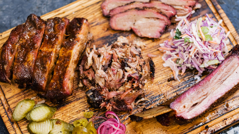 Assortment of smoked meat and sides on wooden board
