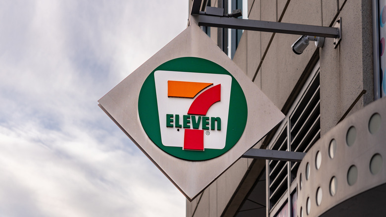 7-Eleven sign hanging from building against blue sky background