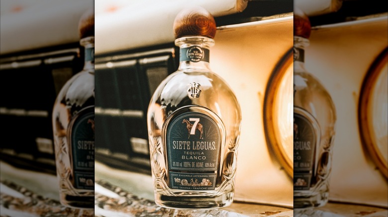 Bottle of Siete Leguas Blanco on the bumper of an old truck
