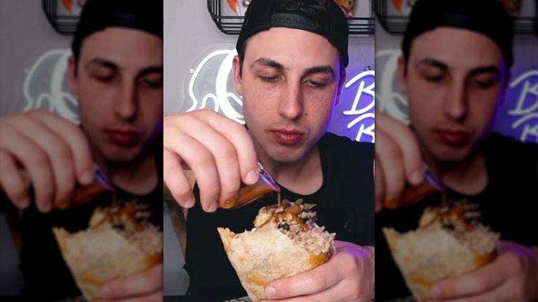 Person pouring Chipotle honey vinaigrette onto burrito