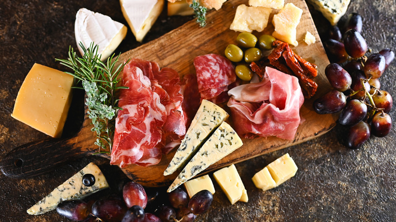 Cheese and charcuterie board with fruit and herbs