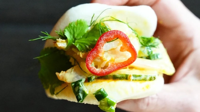 Bao bun stuffed with shrimp, cilantro, dill, green onions, and sliced pepper