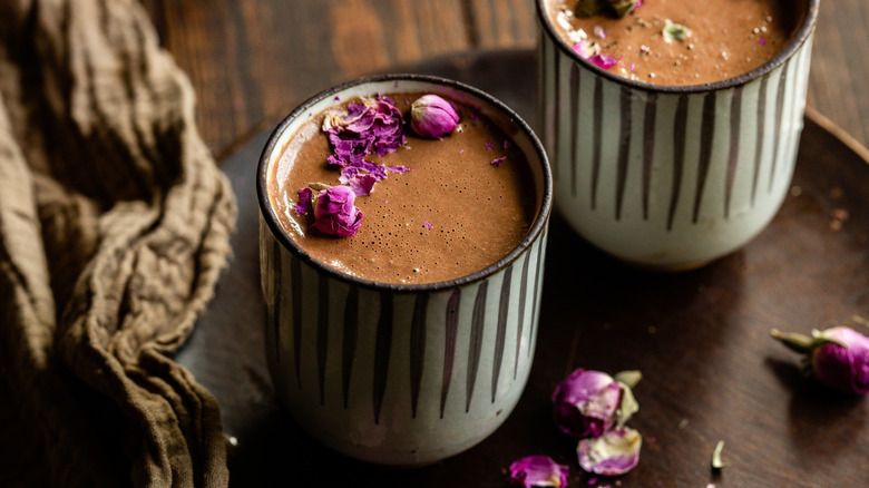 Mugs of hot chocolate with floral garnish