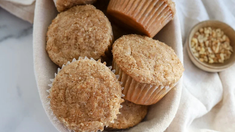 Maple Walnut Muffins in bowl lined with towel with fresh walnuts on the side