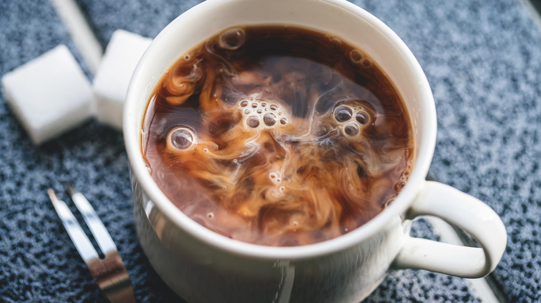 Cup of coffee swirling with freshly-added creamer