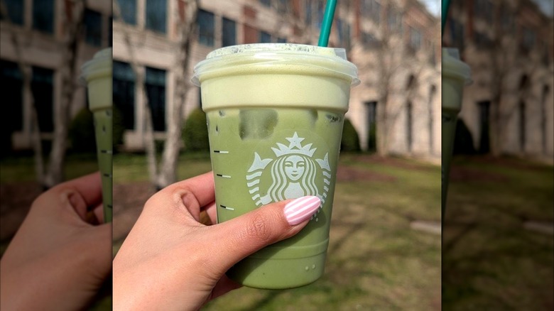 Hand holding Starbucks matcha drink with mango cold foam