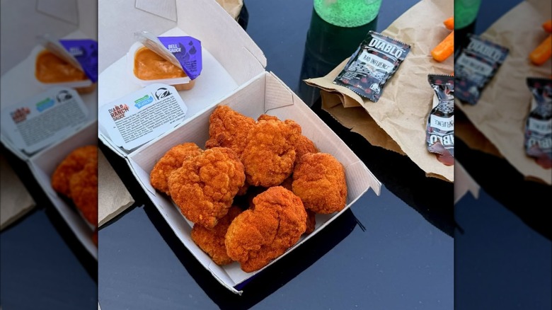 Box of Taco Bell Diablo Dusted Crispy Chicken Nuggets next to sauce packets on black table