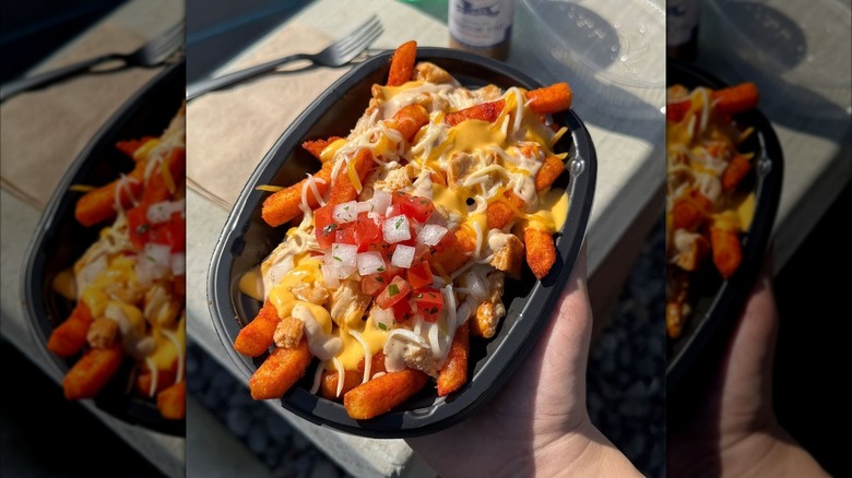 Hand holding black container of Taco Bell Zab's Chicken Ranch Nacho Fries