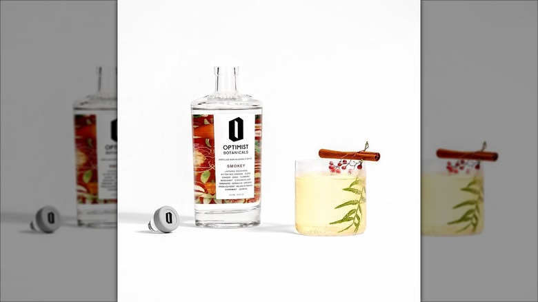 Optimist botanicals smokey bottle next to glass with drink