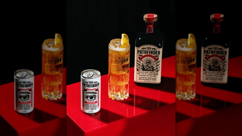 The Pathfinder bottle and can next to highball glass on red table