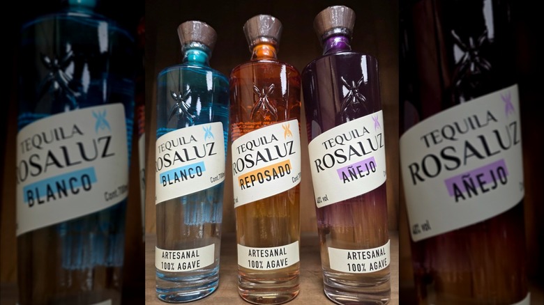 Three bottles of Tequila Rosaluz in blue, orange, and purple bottle