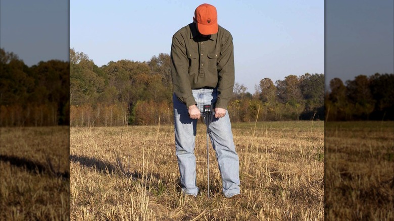 Person using a soil compaction tester in a field