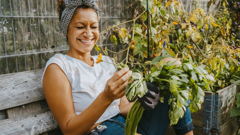 Smiling person sitting in the garden holding plant
