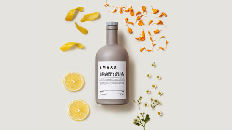 A bottle of AMASS vodka surrounded by lemon, marigold and chamomile
