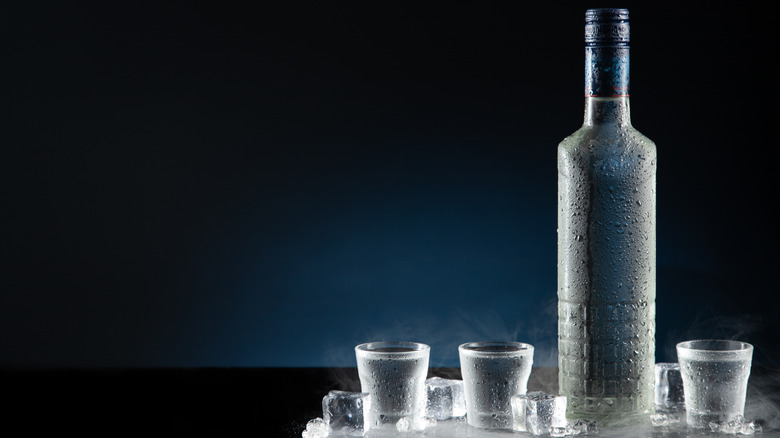 A chilled bottle with three chilled glasses and ice cubes