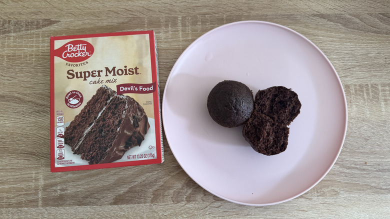 Left: a box of cake mix; right: two chocolate cupcakes, one halved